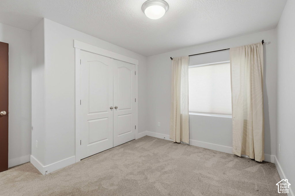 Neutral-toned carpeting, white walls, and a window with blinds and drapes