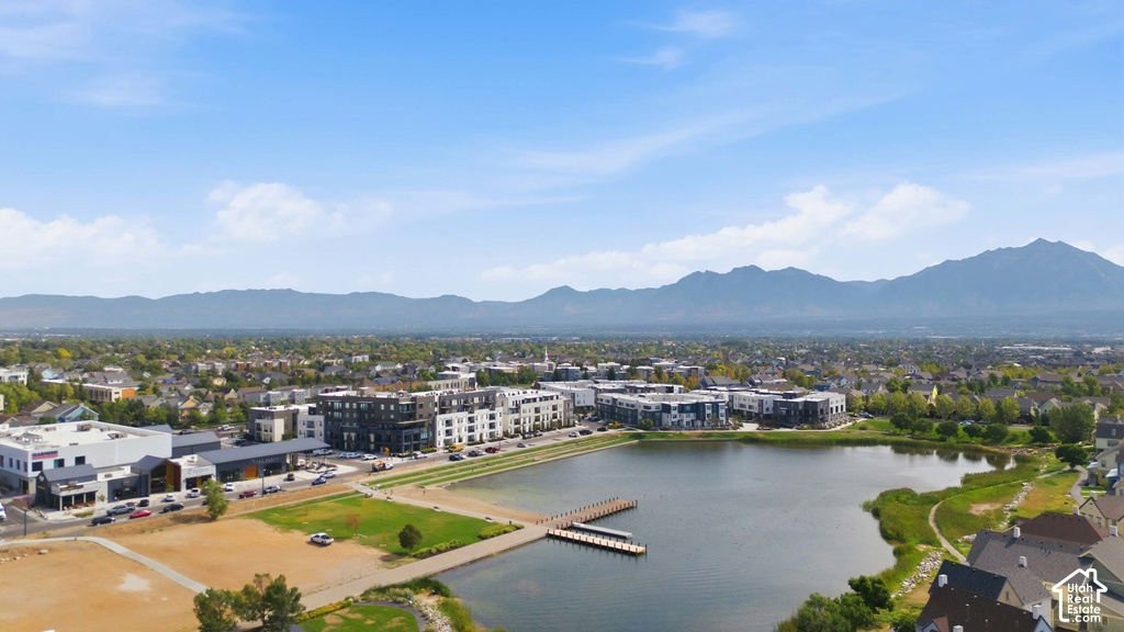 Waterfront property featuring a dock, surrounding residential structures, and distant mountains