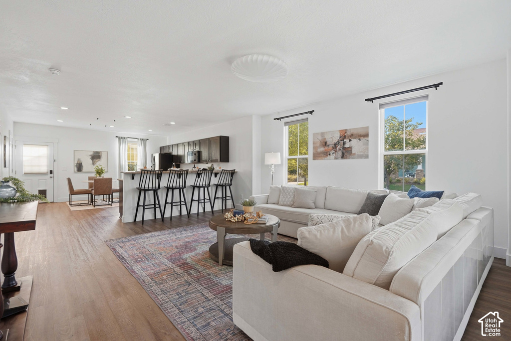 Open-concept living area featuring wood-finish flooring, recessed lighting, and ample natural light from multiple windows