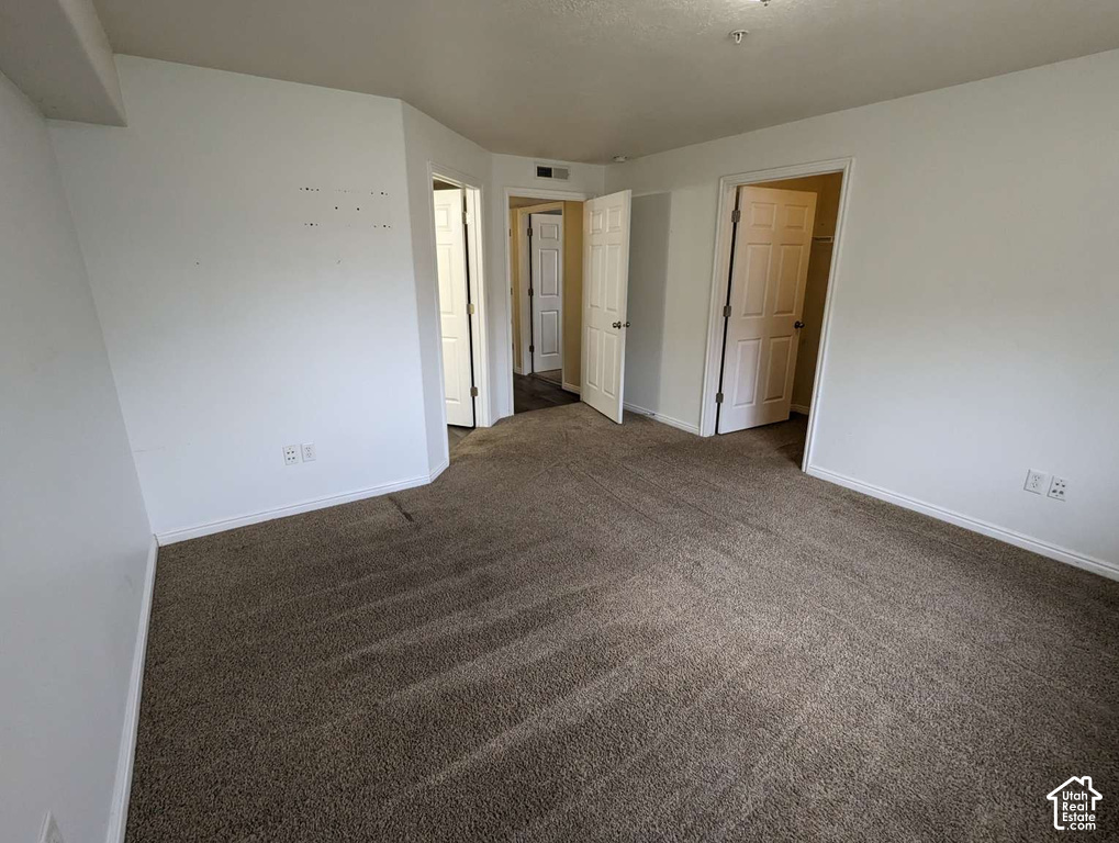 Carpeted flooring, white walls, multiple doorways, and white trim