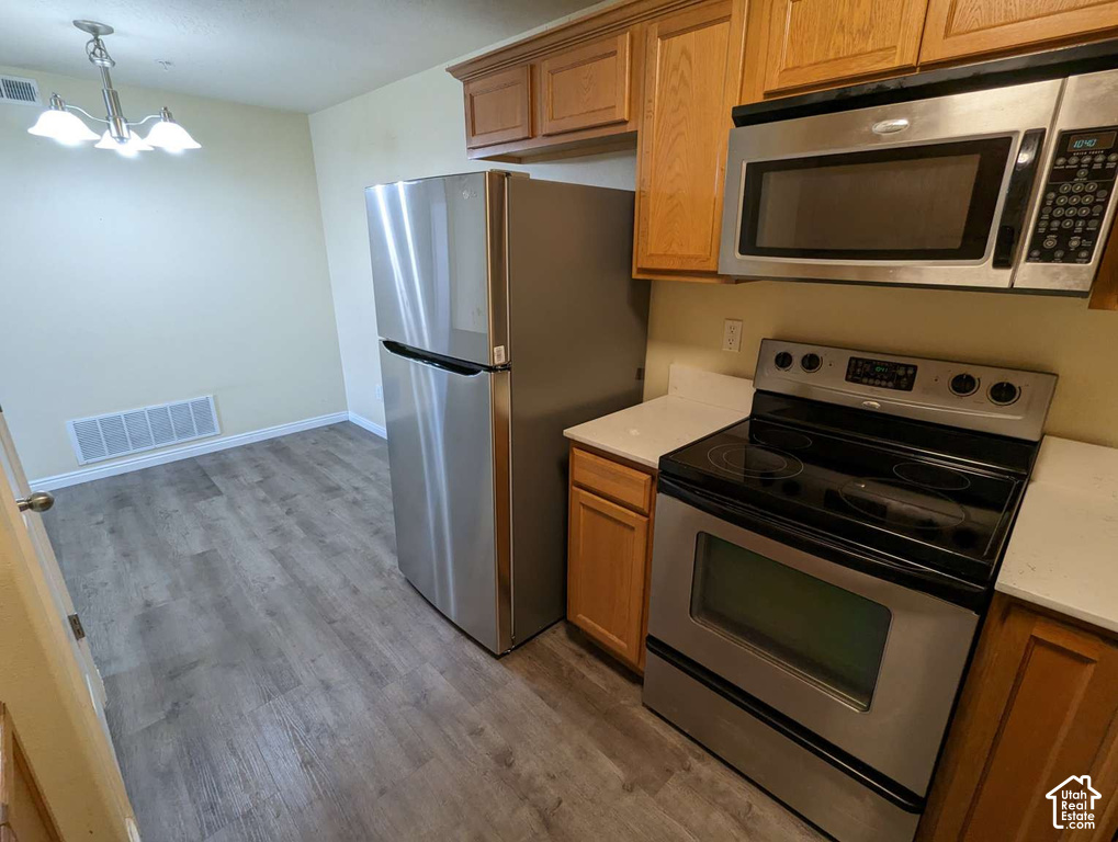 Stainless steel appliances, wood-finish flooring, light-toned cabinetry, and white countertops