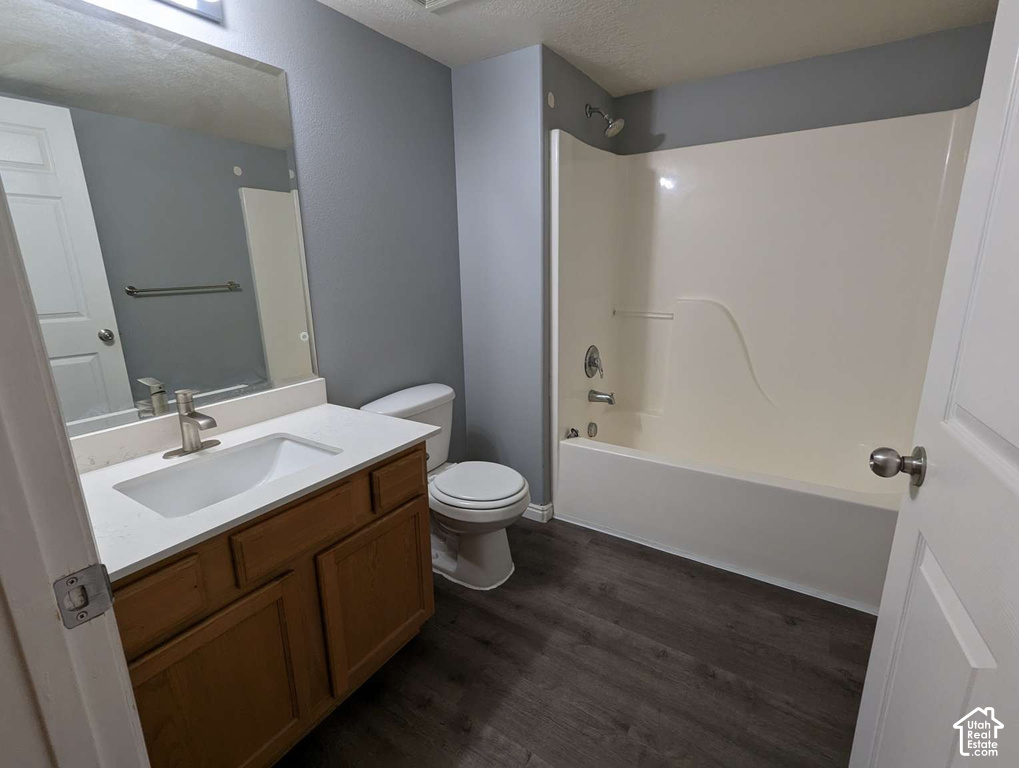 Wood-finish flooring, single vanity with light-toned countertop, integrated sink, and brushed nickel faucet