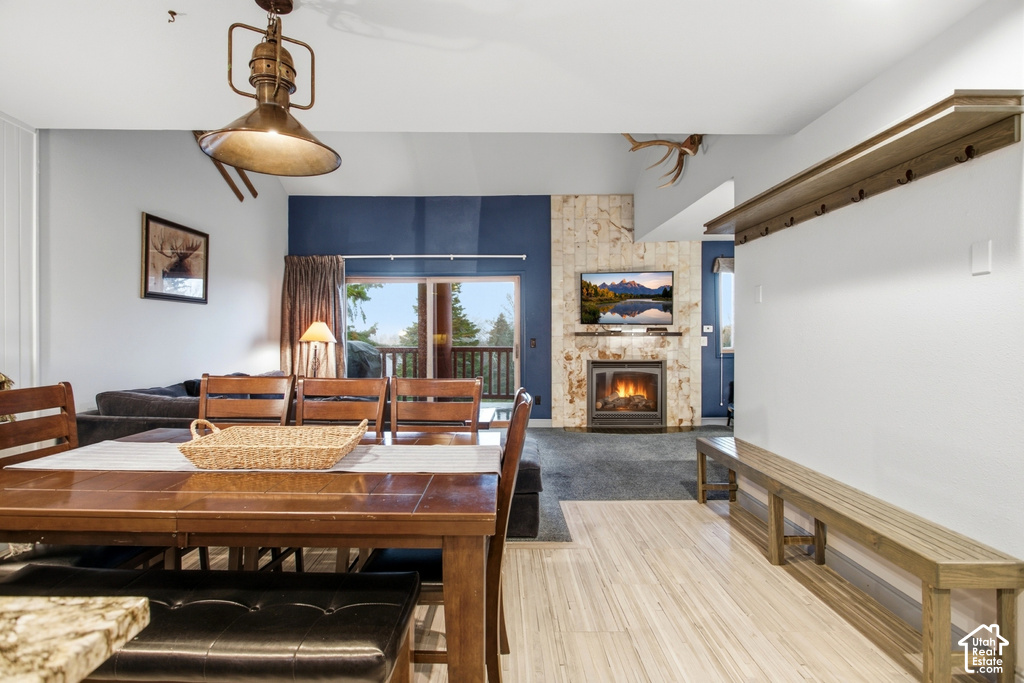 Wood-finish flooring, built-in fireplace with stone-finish surround, wood dining table with seating, sliding glass door, and a built-in bench with coat hooks