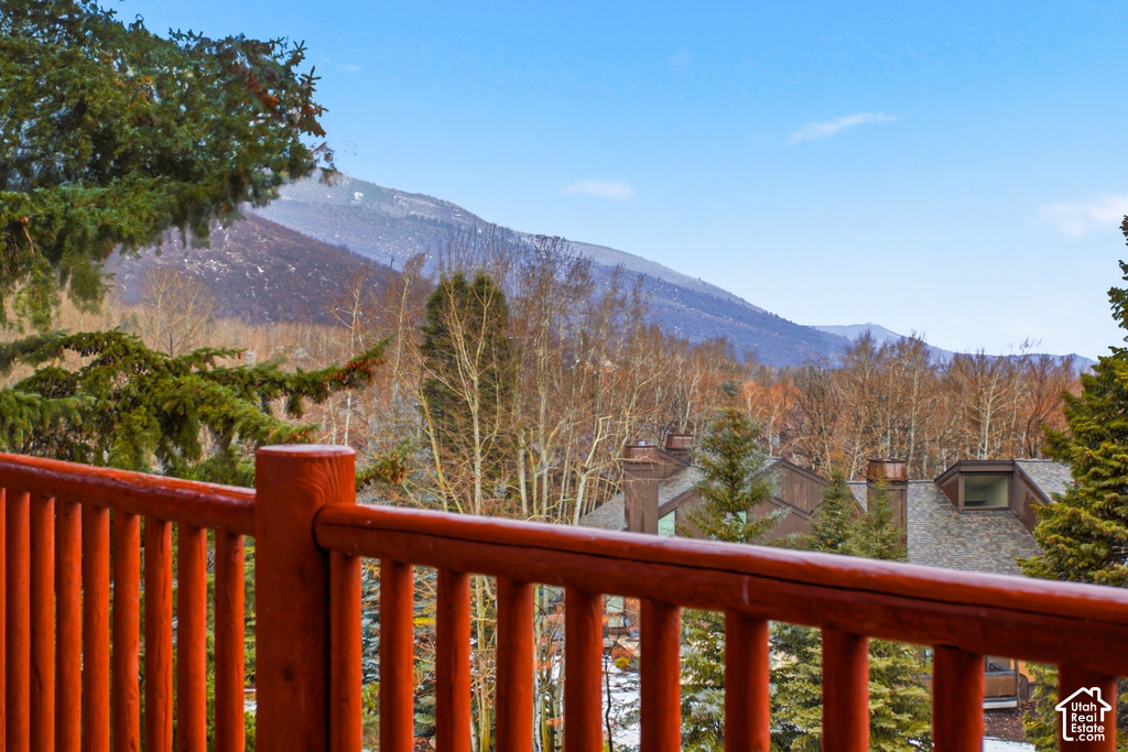 Wood-tone railing with mountain scenery and distant rooftops