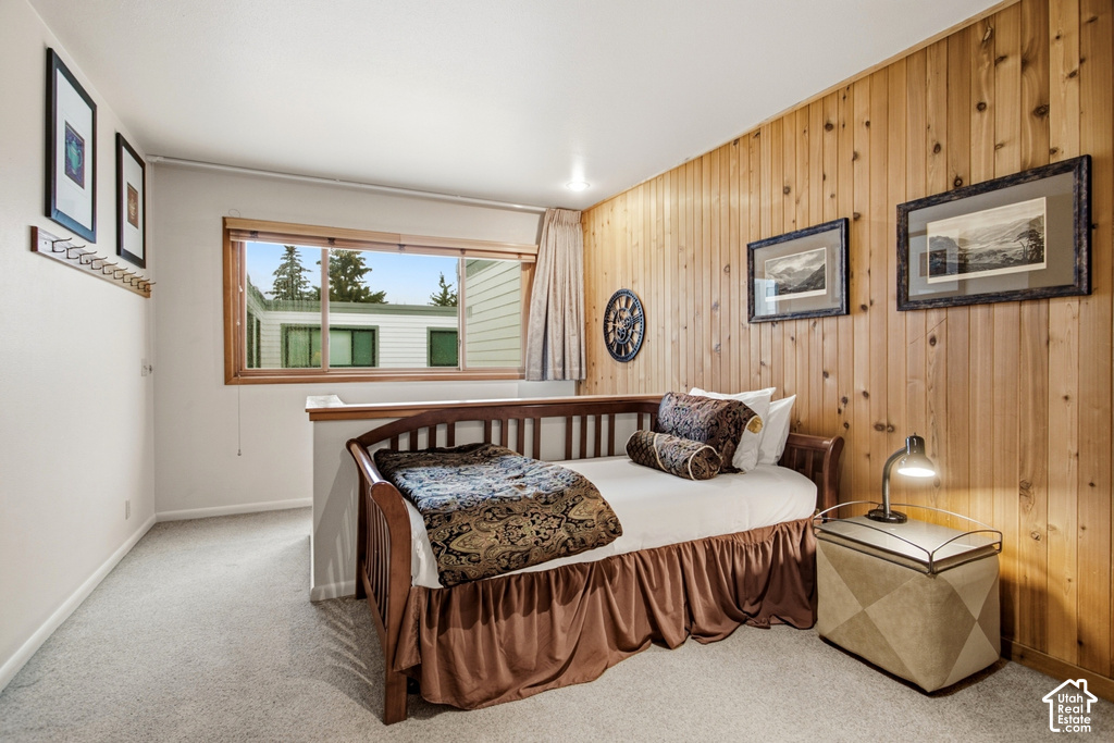 Wood-paneled accent wall, light-colored carpeting, and a window with wood trim