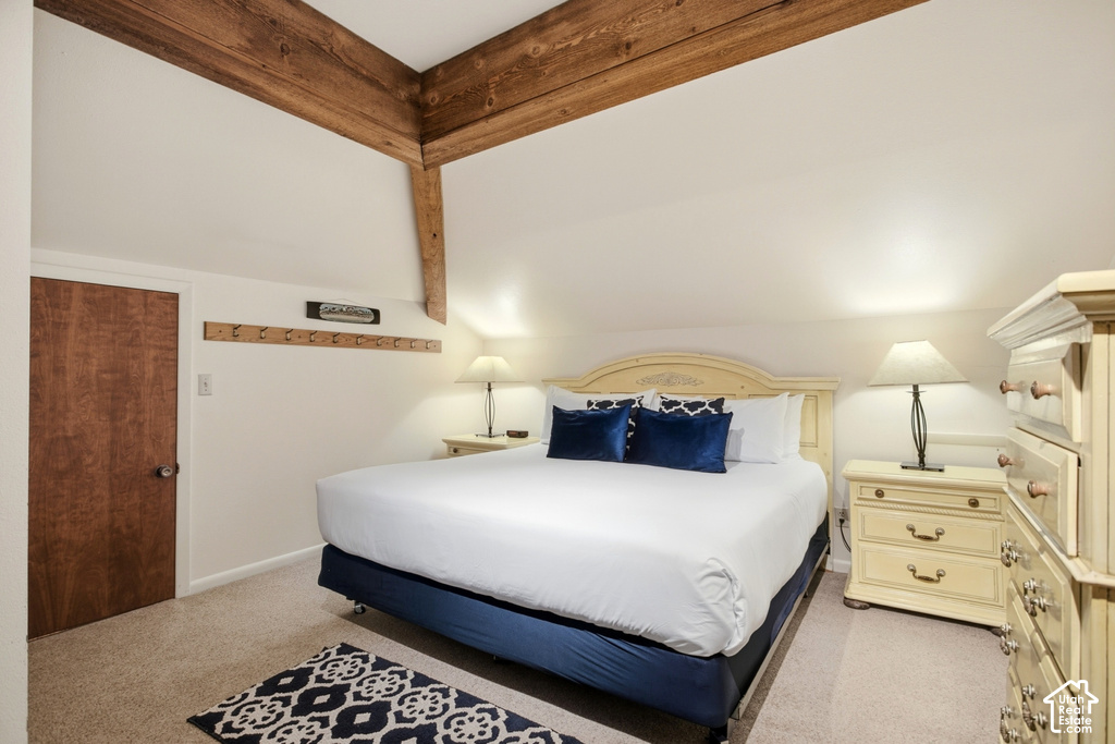 Exposed wood beam ceiling, wood-finish door, wall-mounted wooden rack, recessed lighting, and carpeted flooring