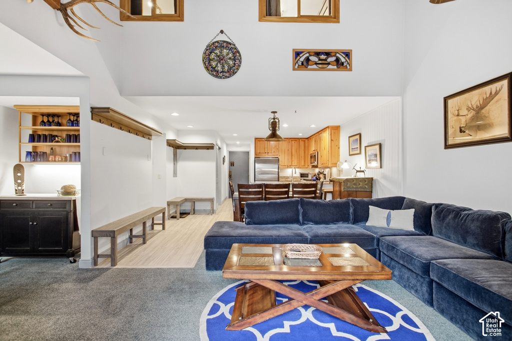 Vaulted ceilings with recessed lighting, wood-finish flooring, a built-in wet bar with cabinetry, and a kitchen featuring wood cabinetry and stainless steel appliances