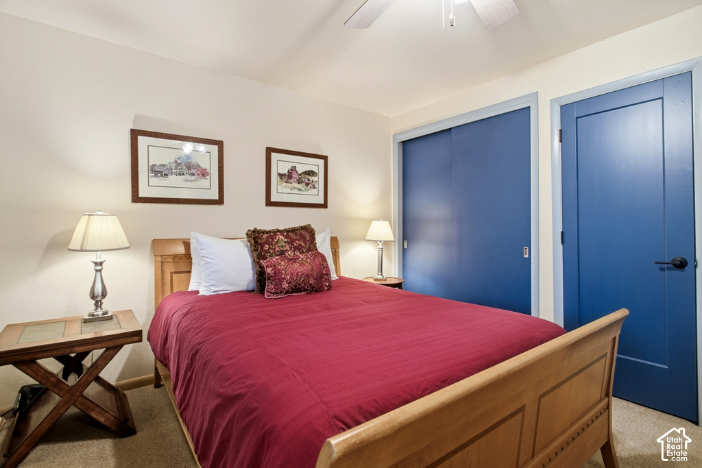Ceiling fan with light fixture, two panel doors with matte black hardware, and sliding closet doors