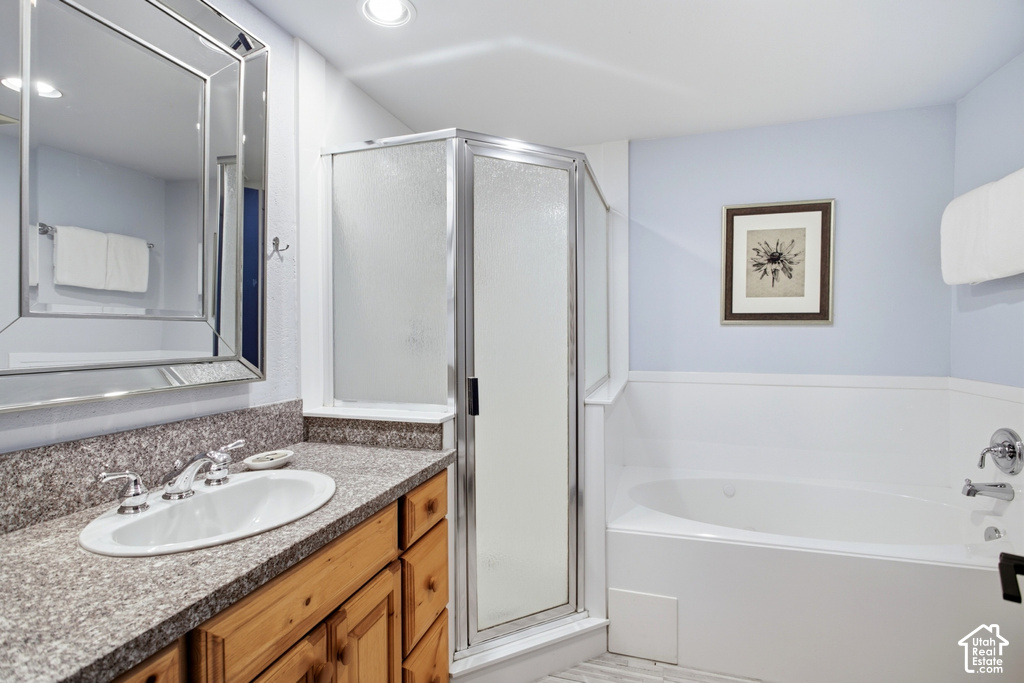 Built-in corner shower with a frameless glass enclosure, a white soaking tub, wood-finish vanity with a drop-in sink, and a framed mirror
