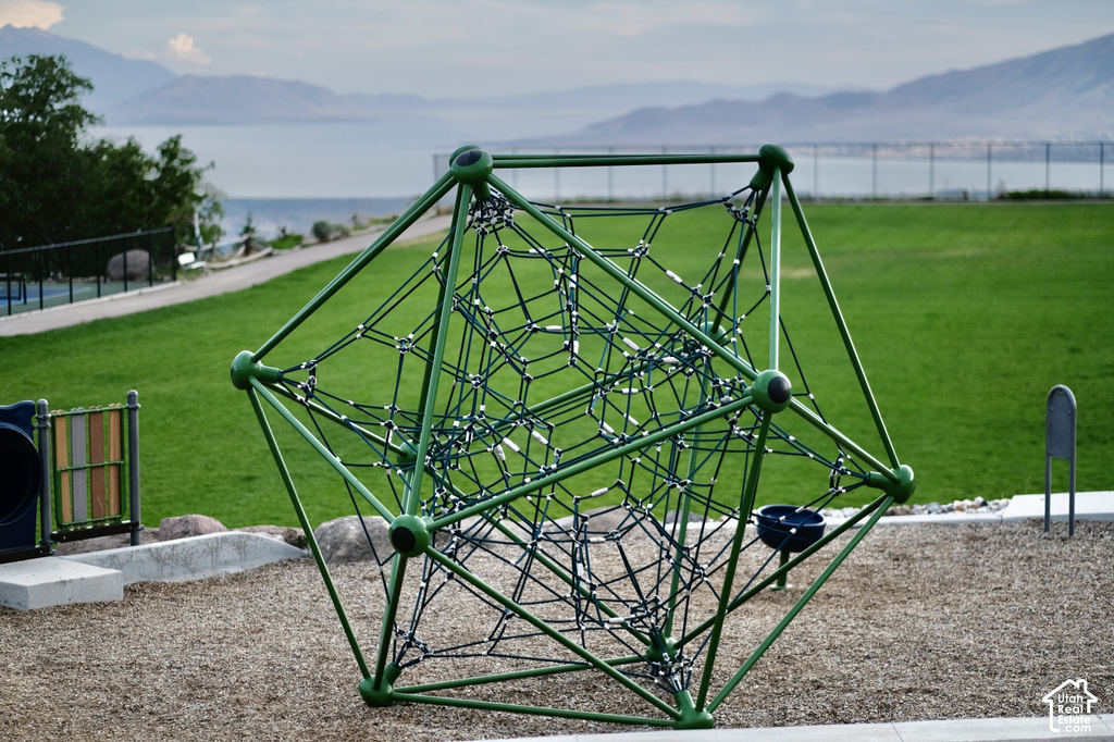 Recreational climbing structure on a woodchip surface, bordered by a substantial grassy area