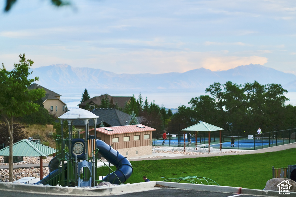Expansive recreational grounds featuring a modern playground with multi-level slide structure, manicured lawn, and resort-style swimming pool with surrounding decking