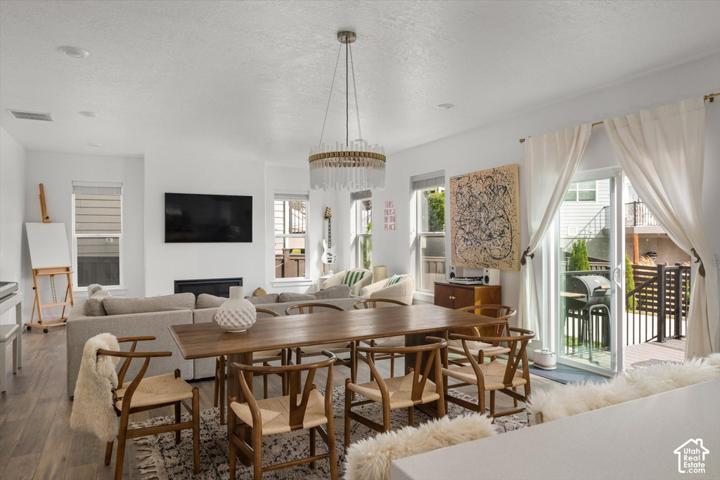 Open-concept living space with a dining area, a linear fireplace, and wood-finish flooring