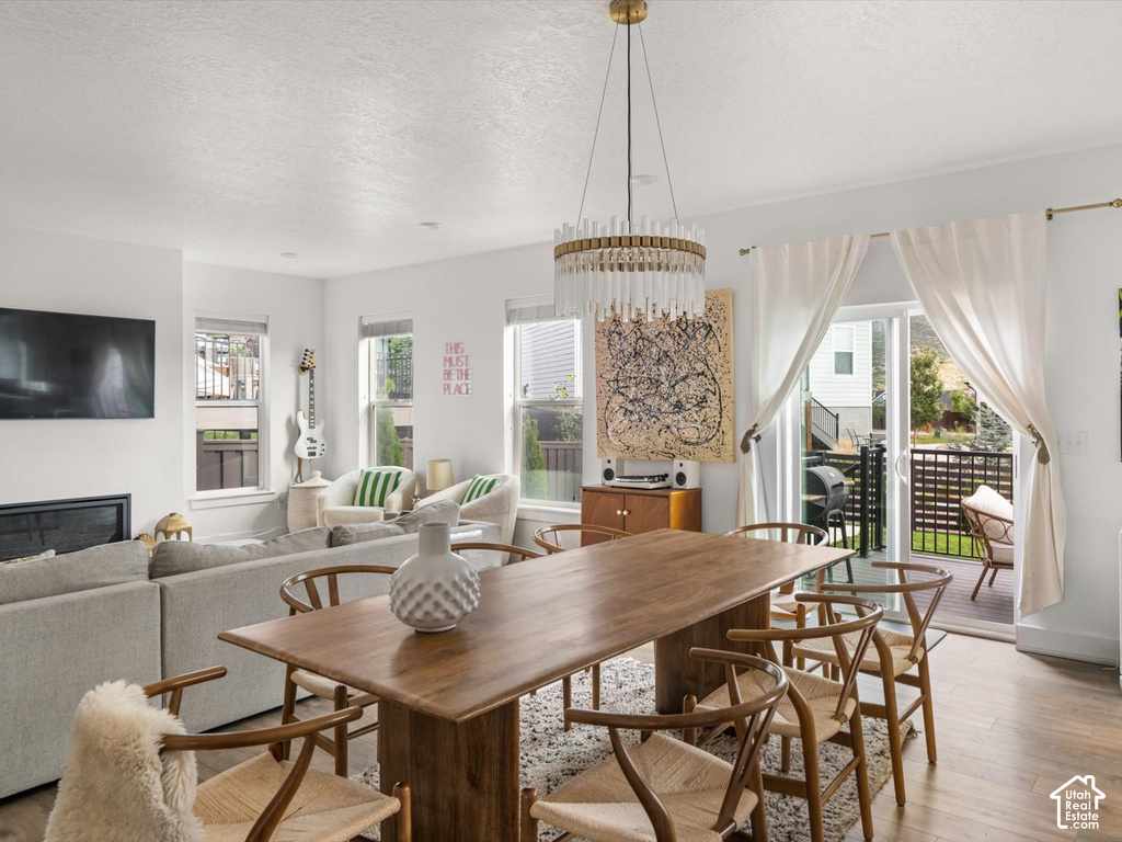 Open-concept living space featuring wood-finish flooring, a contemporary chandelier, a built-in fireplace, and sliding glass doors leading to an exterior balcony