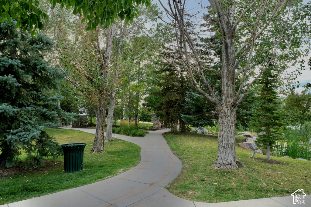 Manicured landscaping with mature trees, paved walking paths, and a tranquil pond feature