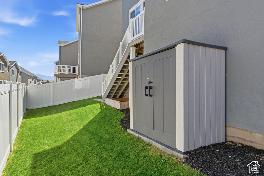 Private backyard featuring a manicured lawn, white privacy fencing, and a built-in storage shed