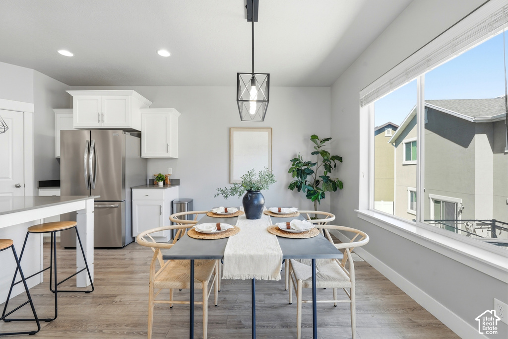Open-concept dining area with wood-finish flooring, a large window, built-in recessed lighting, and a contemporary pendant fixture