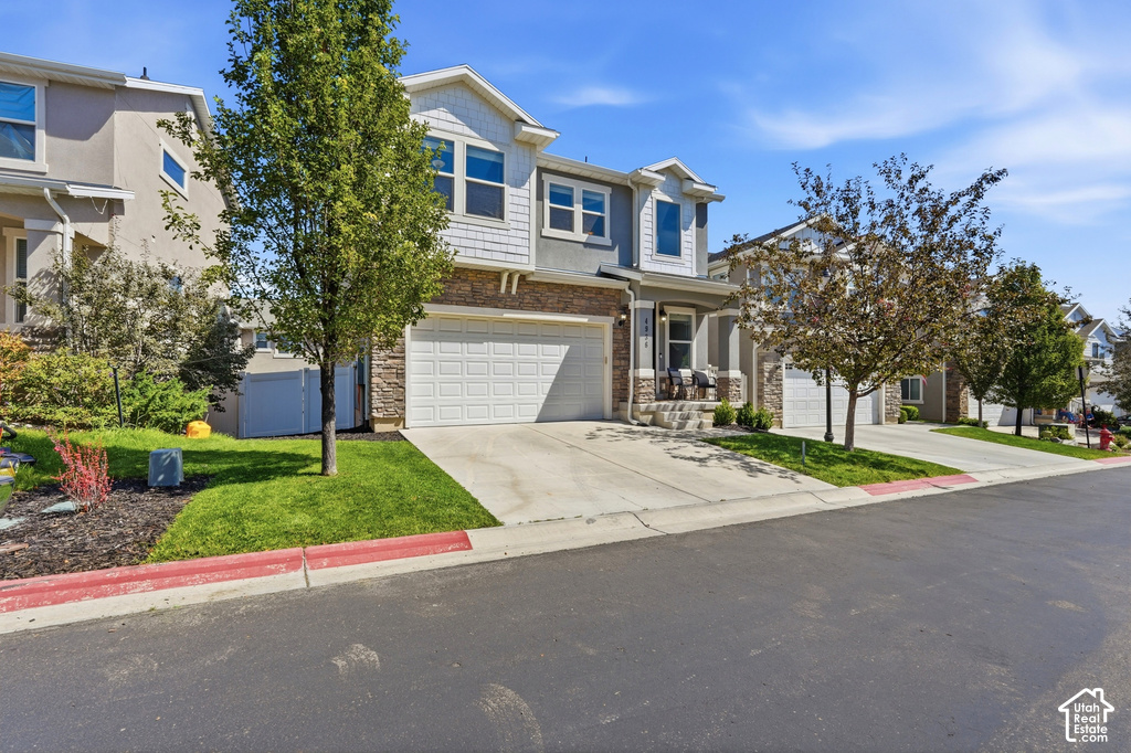 Multi-story residence featuring a two-car garage, stone and siding exterior, and a covered front porch