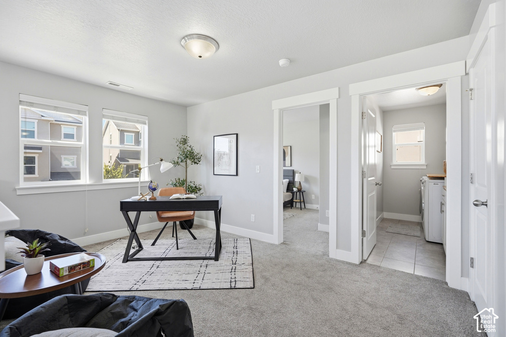 Gray wall paint throughout, two large windows with white trim, gray carpet flooring, and a laundry area with tiled flooring