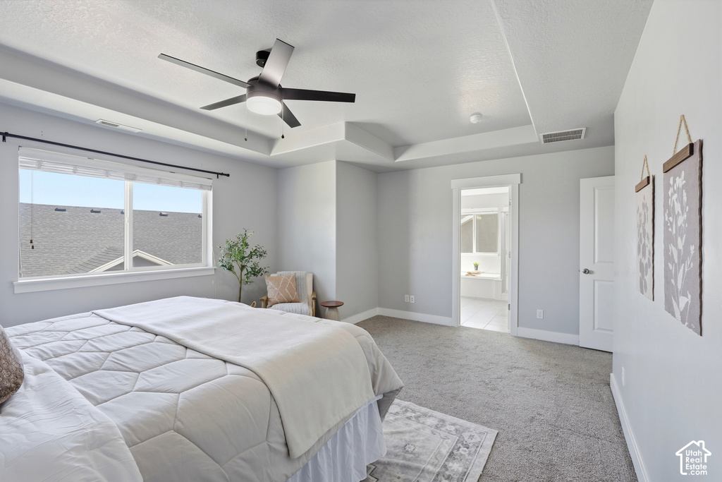 Spacious primary bedroom featuring abundant natural light from expansive windows, neutral paint finishes, carpeted flooring, ceiling fan with integrated lighting, and direct access to an ensuite bathroom
