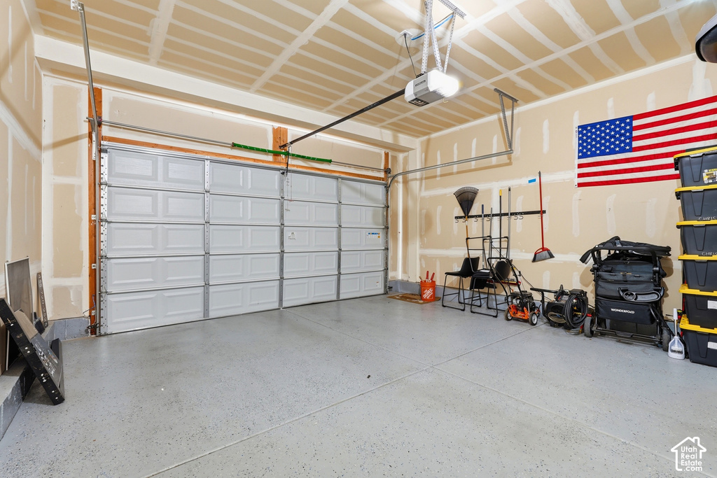 Attached two-car garage with an automatic garage door opener, concrete flooring, and exposed ceiling joists