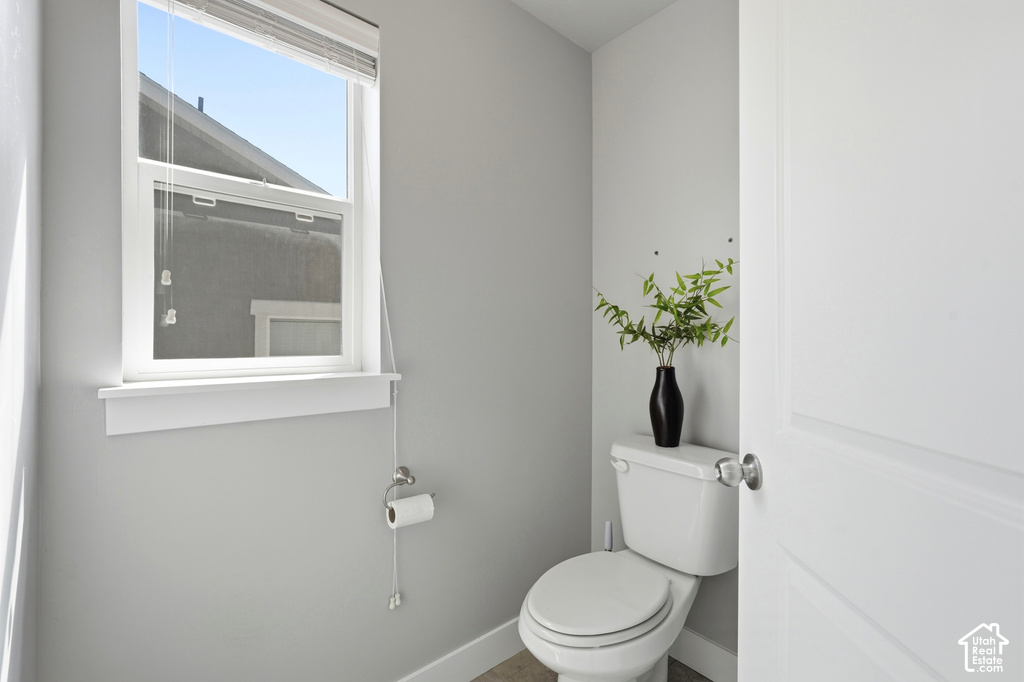 Recessed toilet with a white tank and bowl, featuring a single-pane window with white trim