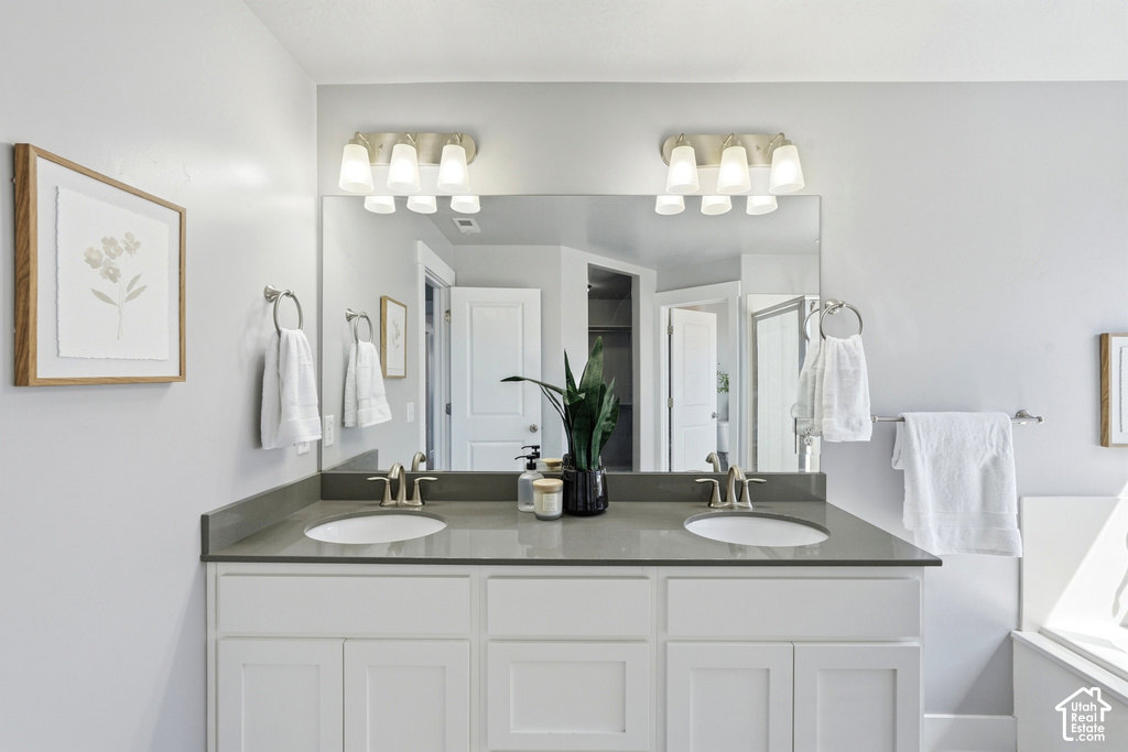 Dual vanity with white cabinetry, undermount sinks, and a dark countertop