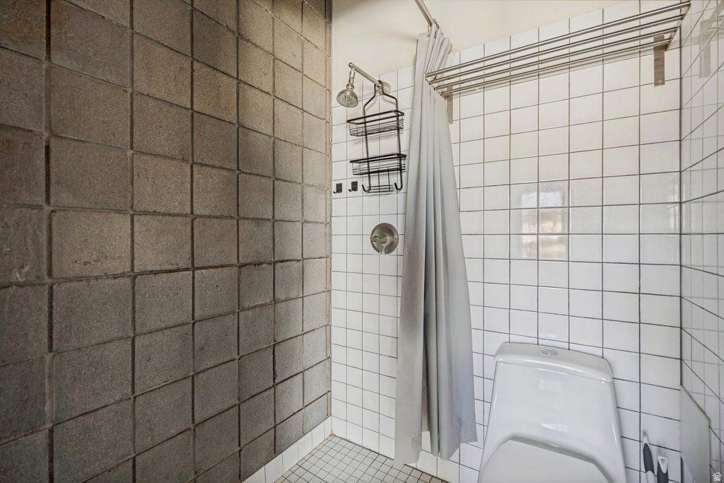 Tile shower surround with a fixed showerhead, integrated shelving, and white square floor tiles