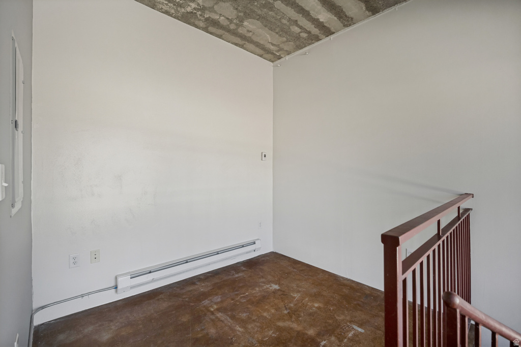 Exposed concrete ceiling, white painted walls, and wood-finish flooring