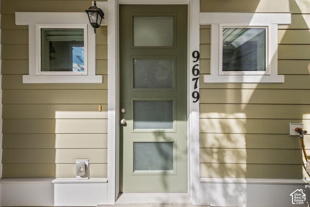 Welcoming front entrance featuring a tall glass-panel door with sidelights, flanked by two symmetrical windows with white trim