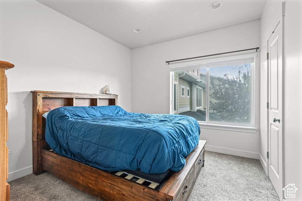 Carpeted flooring, recessed lighting, and a window with roller shades