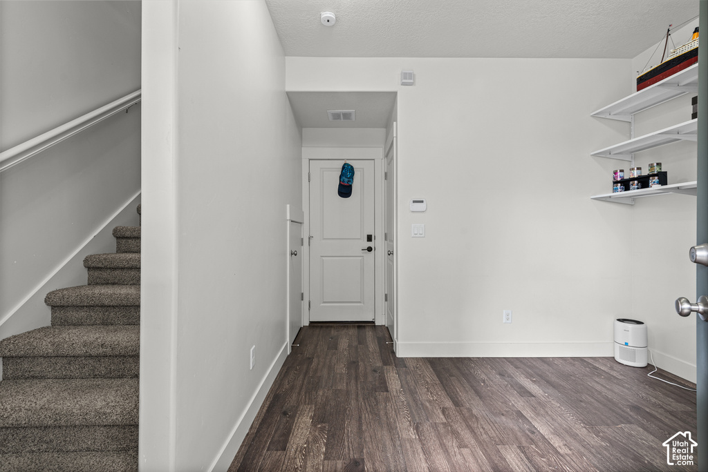 Staircase with carpeted treads, wood-finish flooring, white painted walls, and built-in shelving