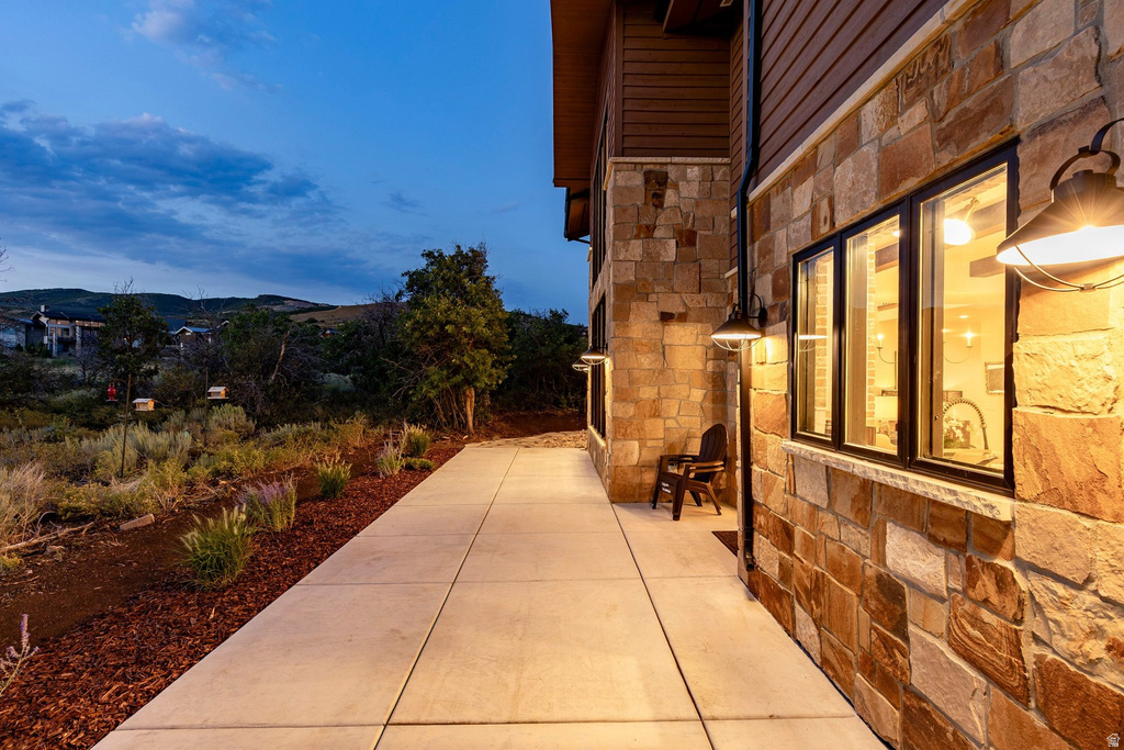 Stone and wood-finish siding exterior with black-framed windows, concrete pathway, and landscaping