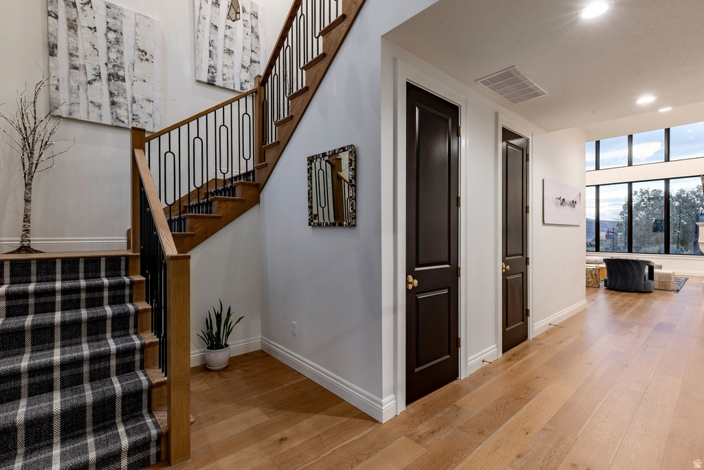 Hardwood flooring throughout, a staircase with black metal balusters and wood handrails, and dark-paneled interior doors