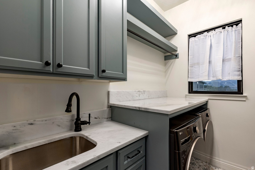 Custom cabinetry with matte black hardware, integrated stainless steel sink, black gooseneck faucet, light-toned stone countertops, and open shelving