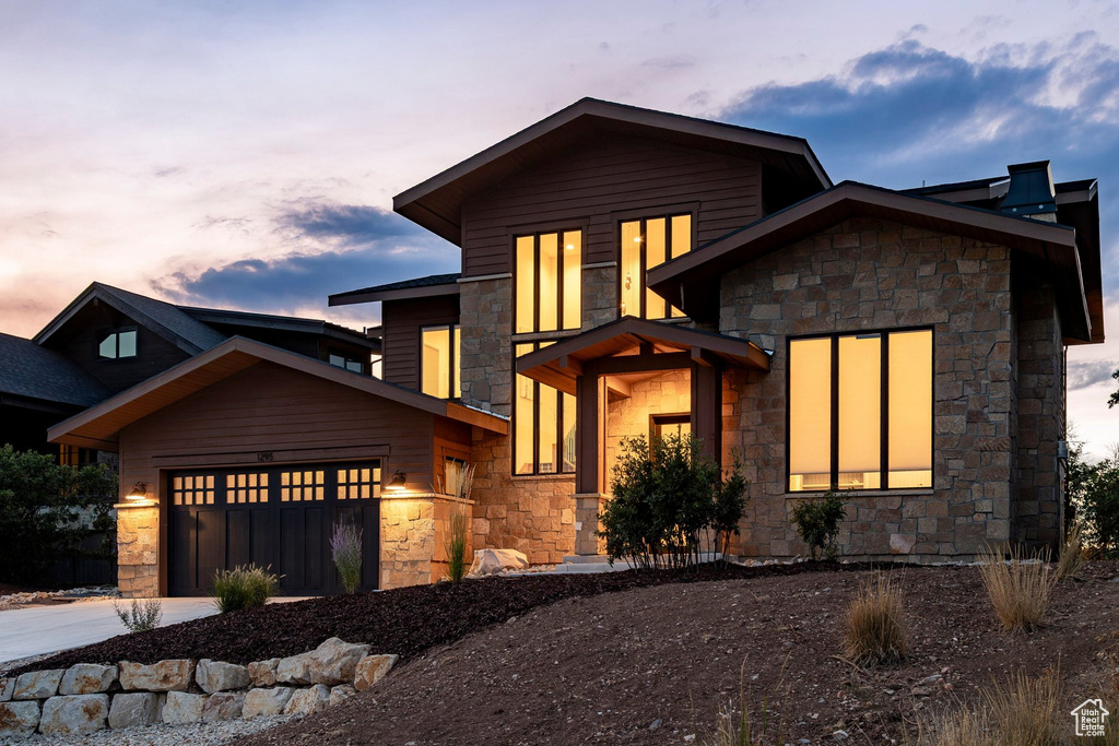 Multi-level exterior featuring stone and wood-finish siding, a covered entry, and an integrated garage with transom windows