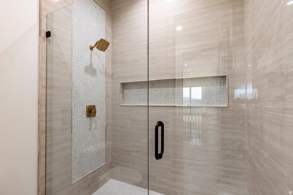 Glass-enclosed shower with a recessed niche, tiled accent wall, and bronze fixtures