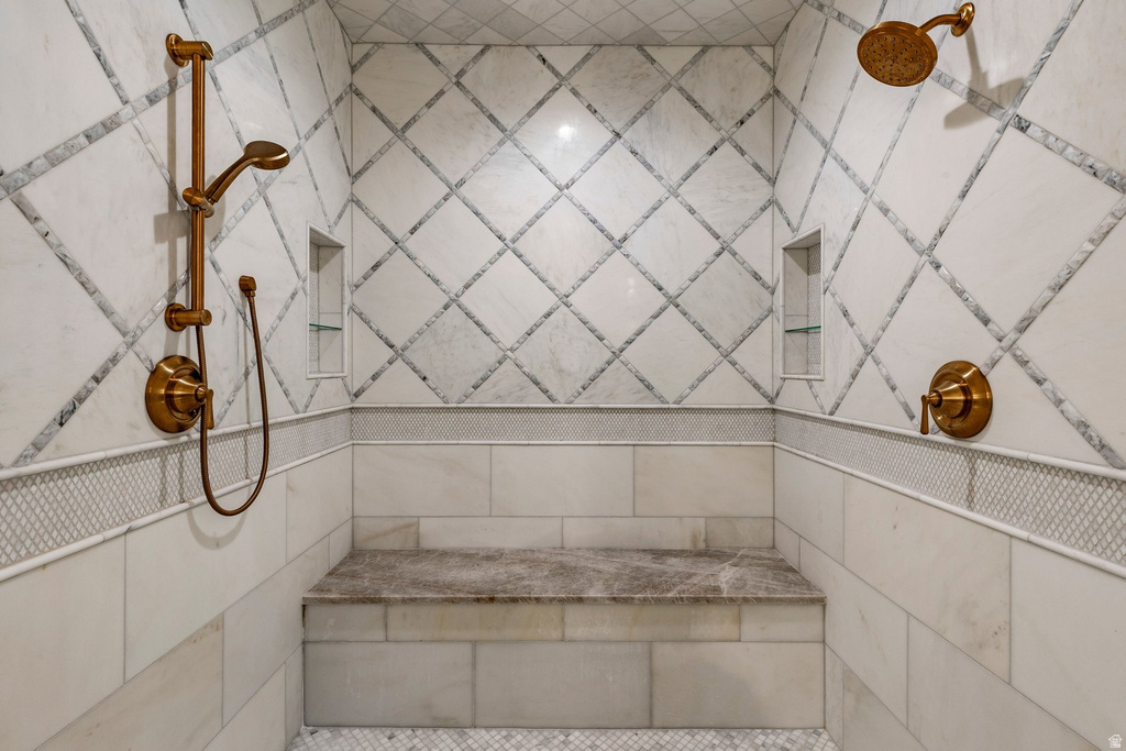 Tiled shower with a built-in bench, two shower heads, and integrated recessed niches