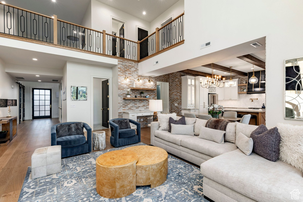 Two-story great room with an open loft, exposed brick accents, recessed lighting, and wood-finish flooring