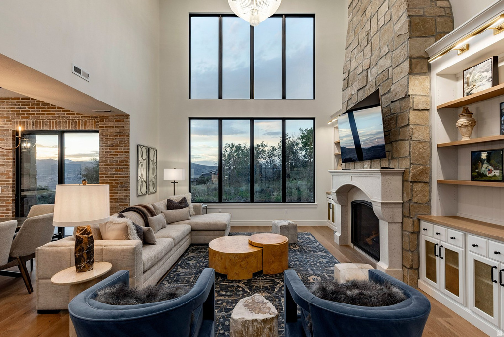 Two-story living area featuring a stone fireplace, built-in shelving, expansive windows, and wood-finish flooring