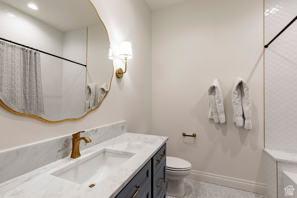 Vanity with a single undermount sink, brass finish faucet, and stone countertop