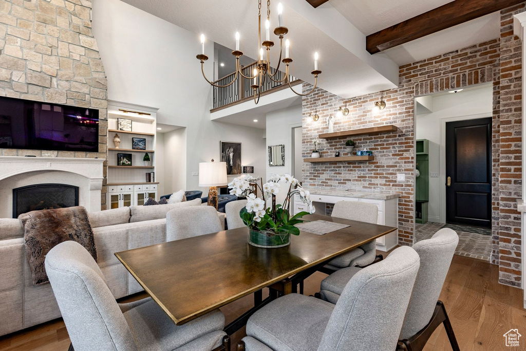 Two-story stone fireplace, built-in shelving, exposed brick wall, wood-finish flooring, and exposed ceiling beams