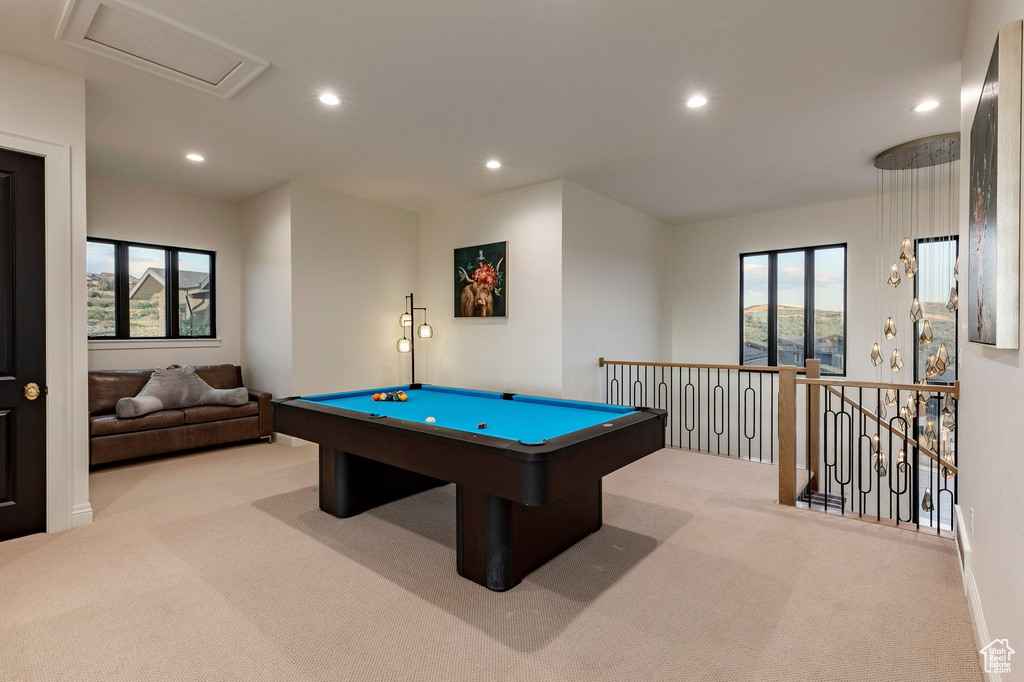 Recessed lighting illuminates the carpeted bonus room, featuring a dark wood newel post and balusters with black metal spindles