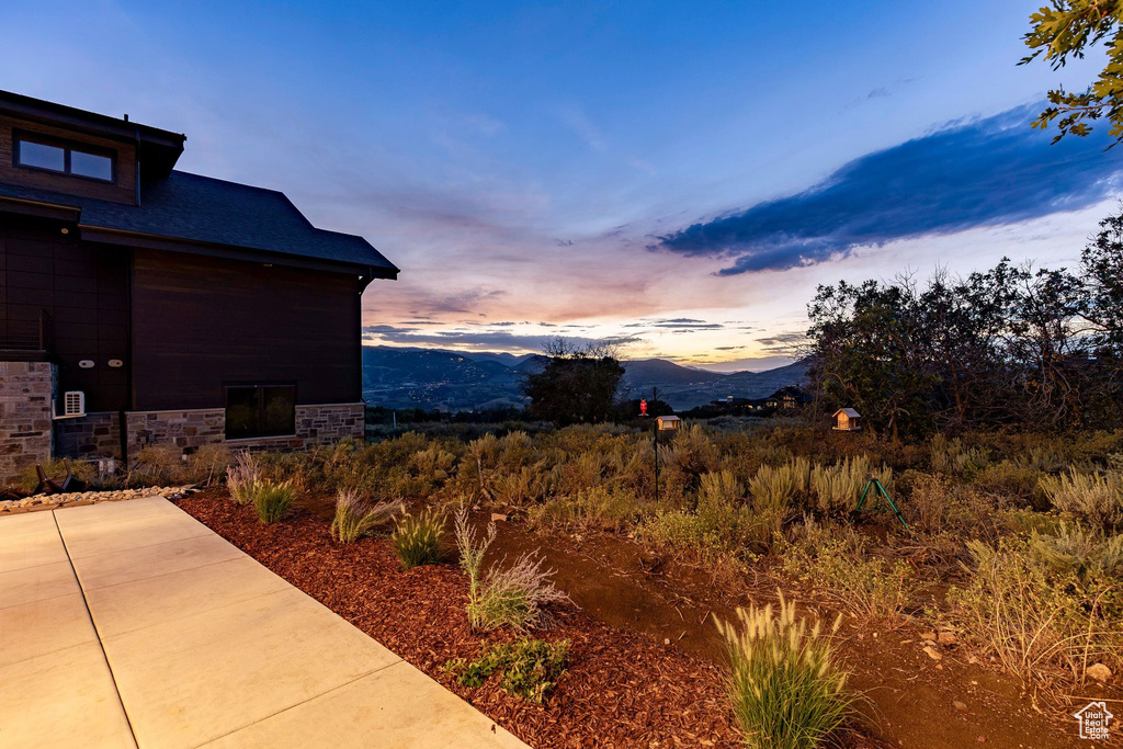Exterior featuring dark wood-finish siding, stone-clad foundation, and a dark shingled roof
