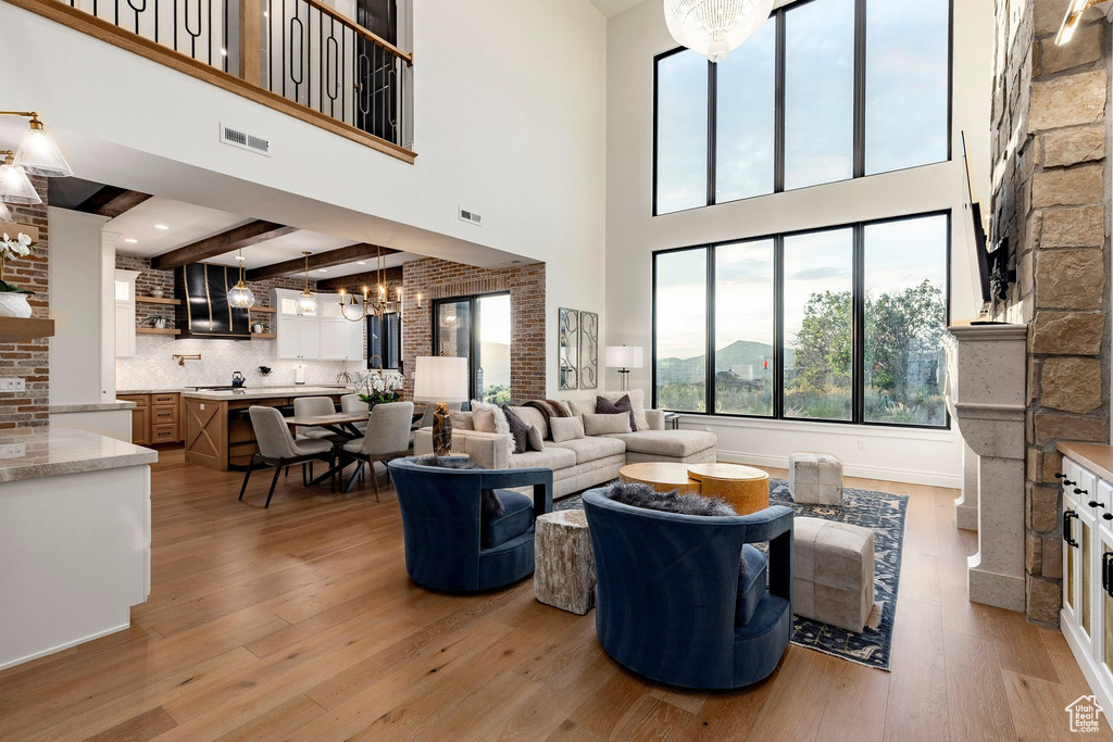 Open-concept living area with soaring ceilings, a stone-clad fireplace, and expansive windows