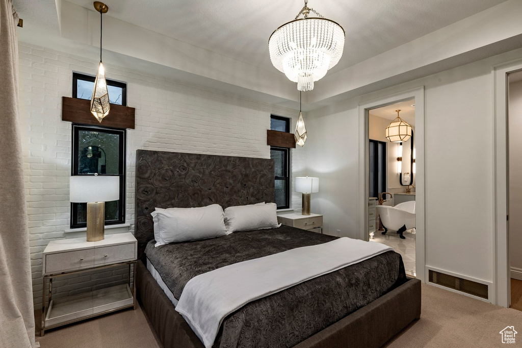 White brick accent wall with a crystal chandelier and recessed lighting