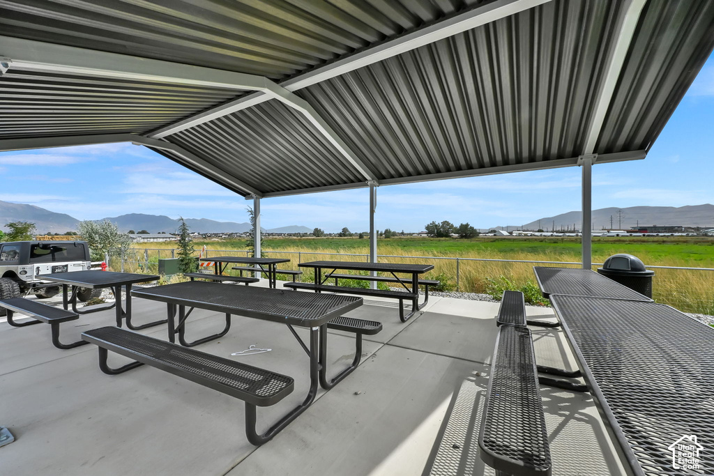 Covered outdoor patio with concrete flooring, multiple picnic tables, and a metal roof structure