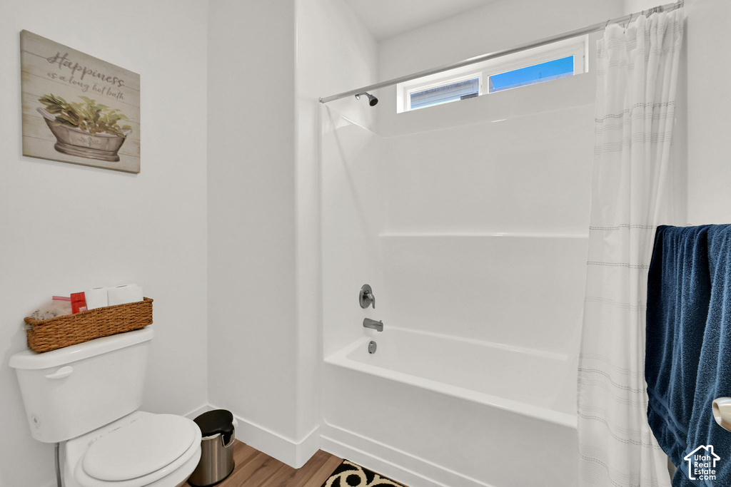 Bathtub with integrated shower, chrome fixtures, and a high transom window