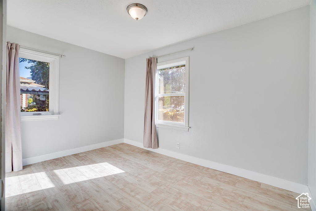 Light-toned wood-finish flooring, white trim, and two windows