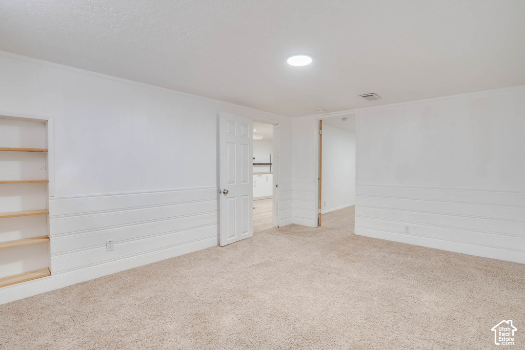 Neutral tone carpet flooring, white painted walls, horizontal paneling, recessed lighting, and built-in shelving