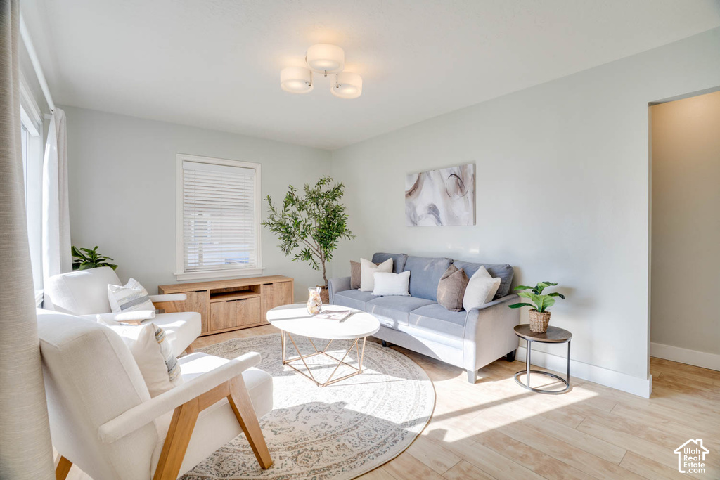 Light-toned wood-finish flooring, recessed ceiling lighting, a built-in window with blinds, and light-colored walls